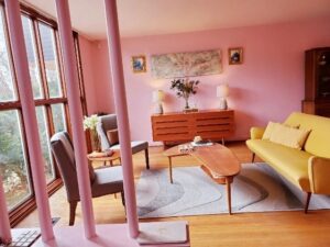 A living room with pink walls and wooden floors
