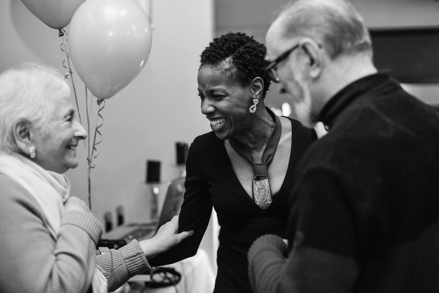 A woman smiling at an event with two men.