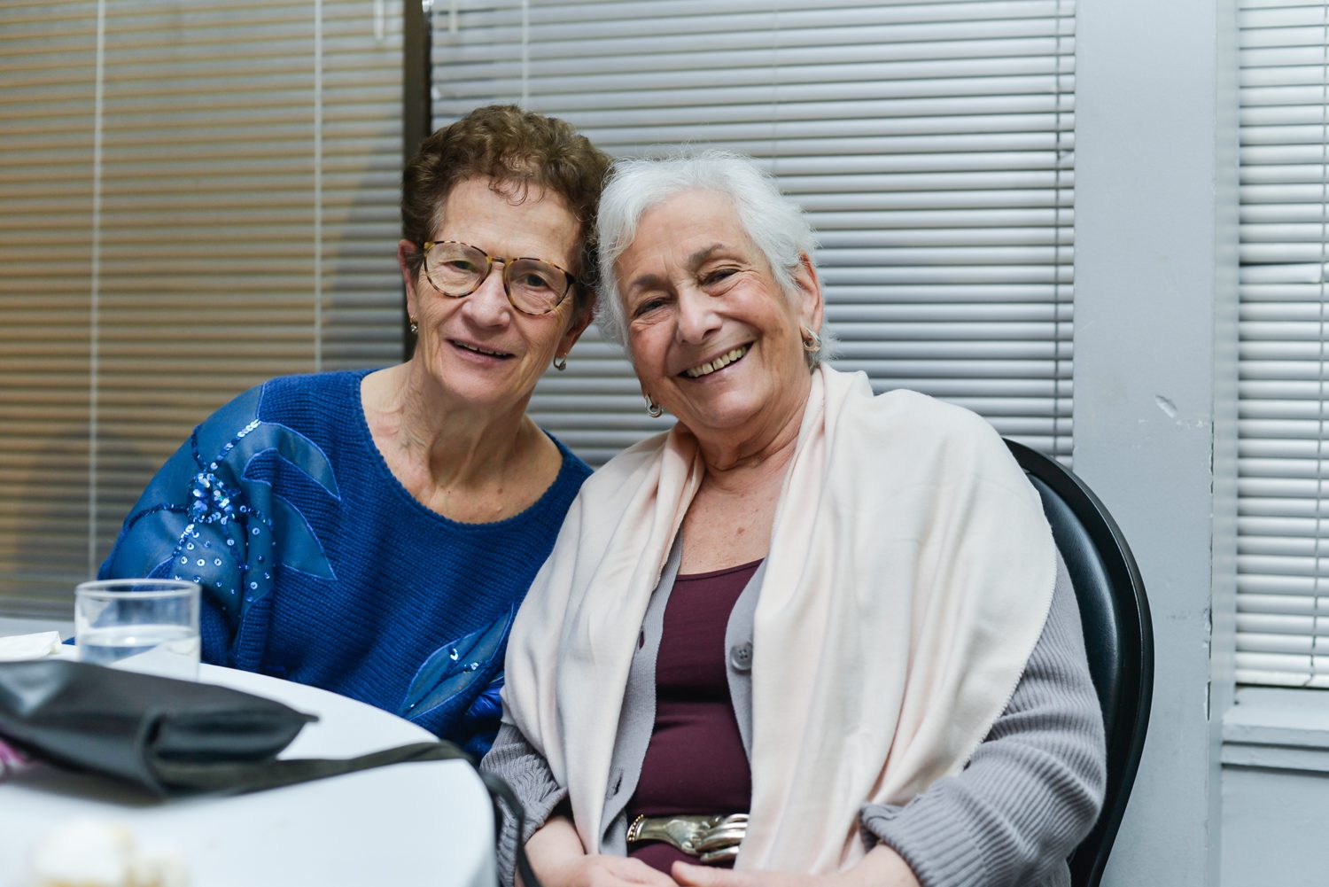 Two women sitting at a table smiling for the camera.