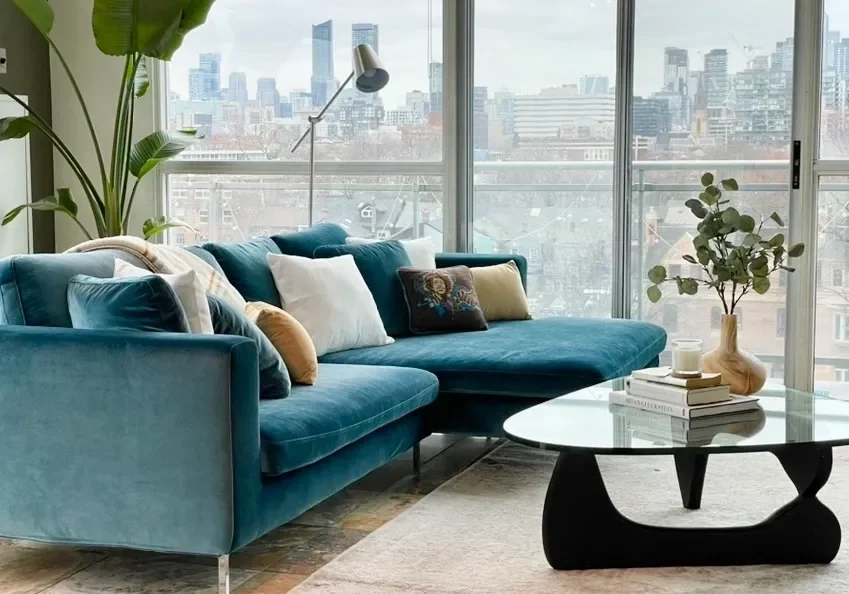 A living room with a large window and a blue couch