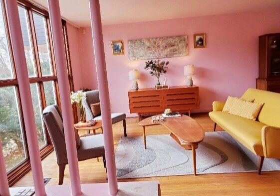 A living room with pink walls and wooden floors